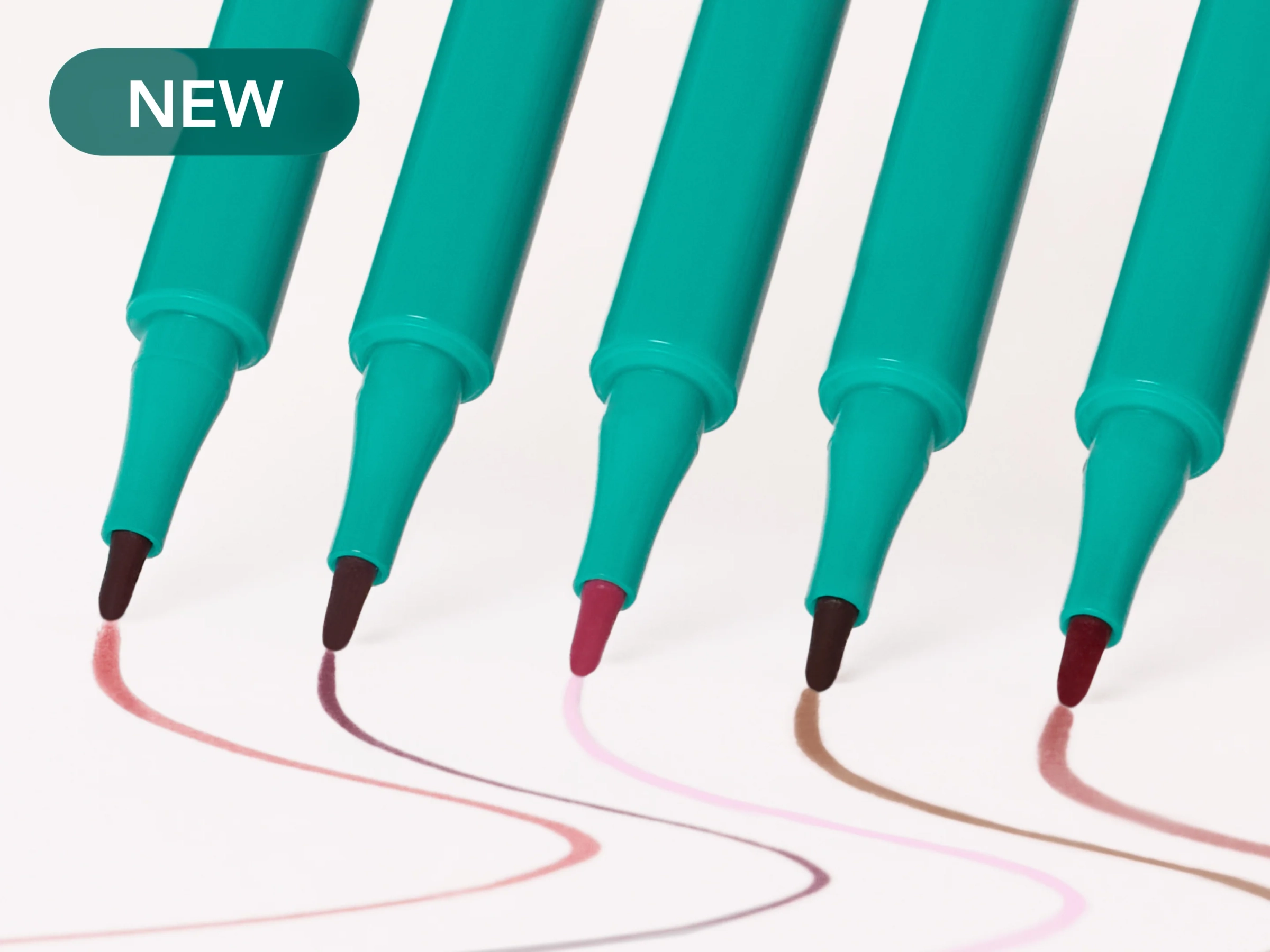 Turquoise lip stain pens fanned out over a pink backdrop