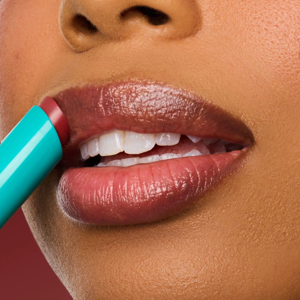 Close view of a lip in deep rose with a turquoise stick