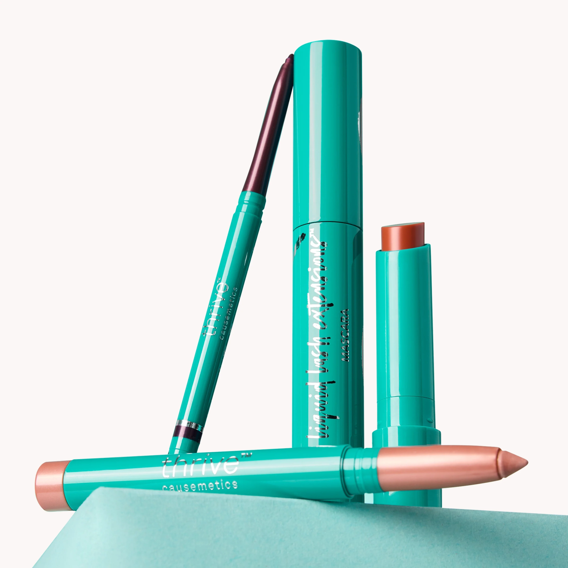 Shimmer stick, mascara and primer arranged on a teal base