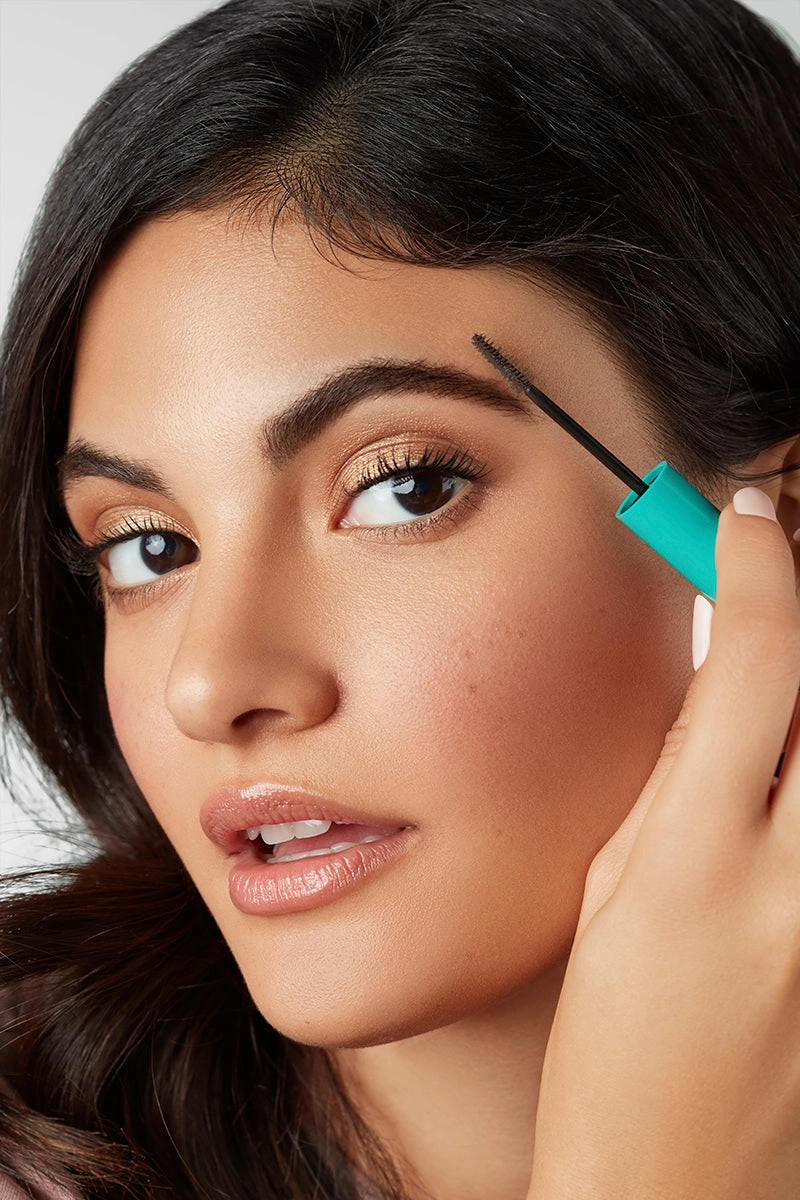Woman with a defined brow holding a brow gel wand