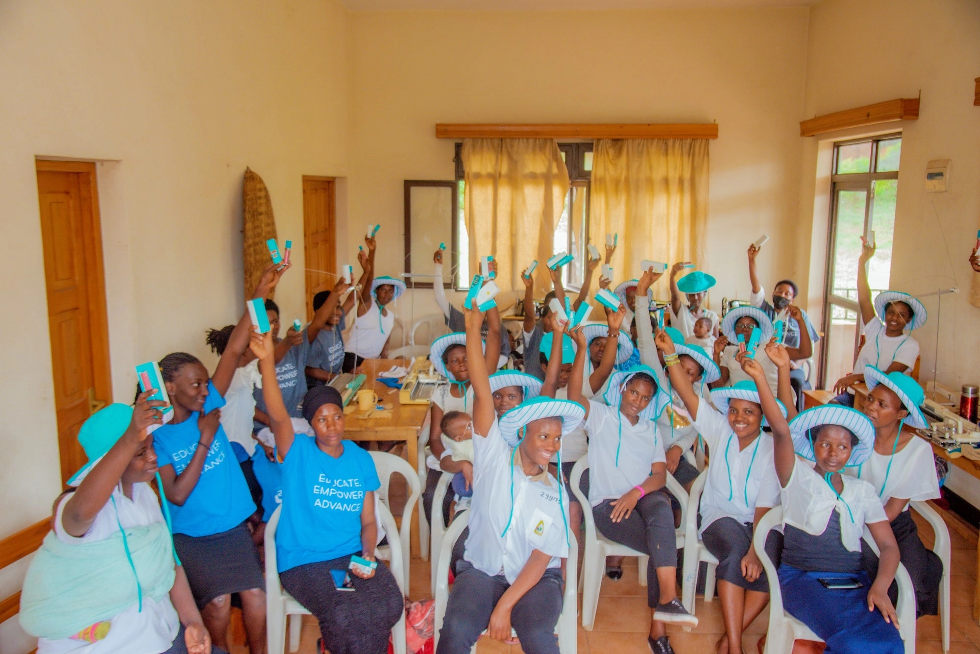 Group of people in matching hats and shirts holding up products in a classroom